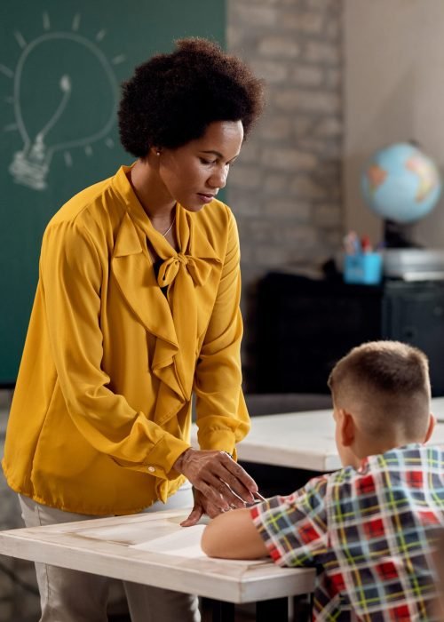 Black teacher assisting her elementary students during a class in the classroom.